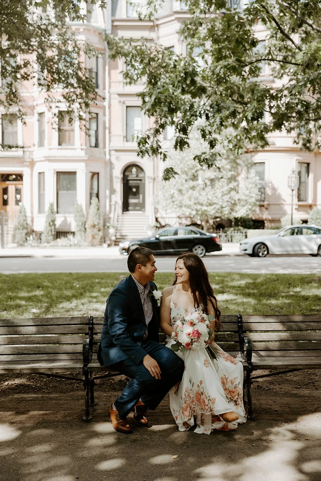 A couple posing for wedding portraits on a bench in Boston