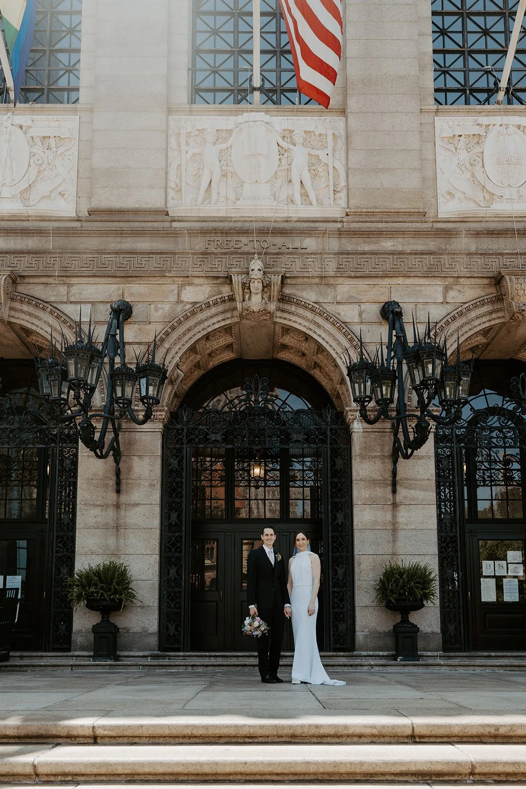 A bride and groom standing outside of the Boston Public Library for elopement photos