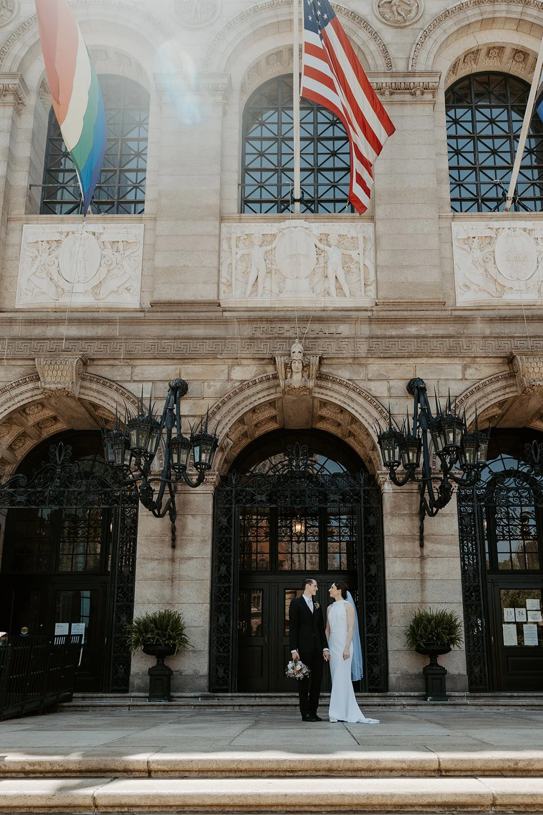 A bride and groom standing outside of the Boston Public Library for elopement photos