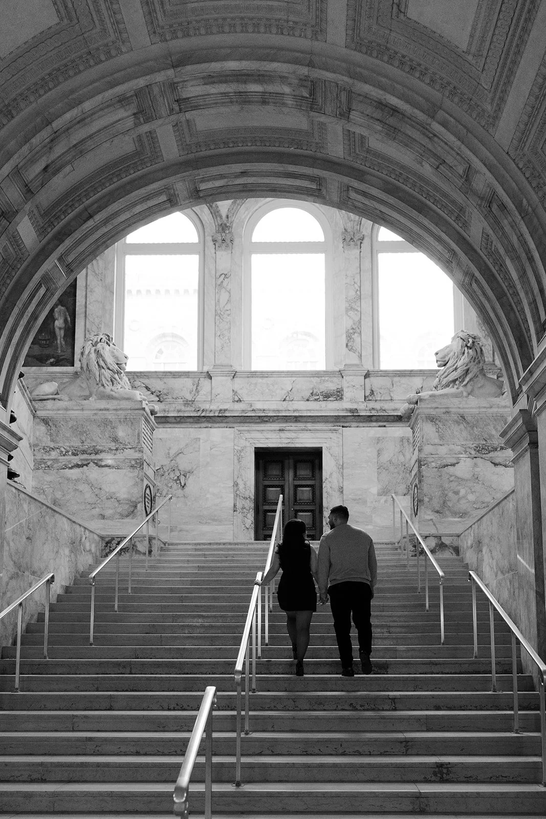 A black and white photo of a couple taking engagement photos in the Boston Public Library