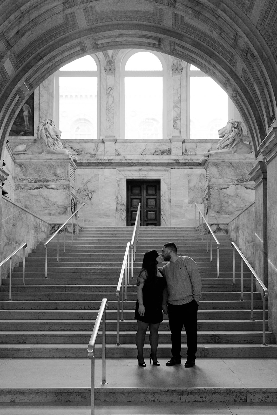 A black and white photo of a couple taking engagement photos in the Boston Public Library