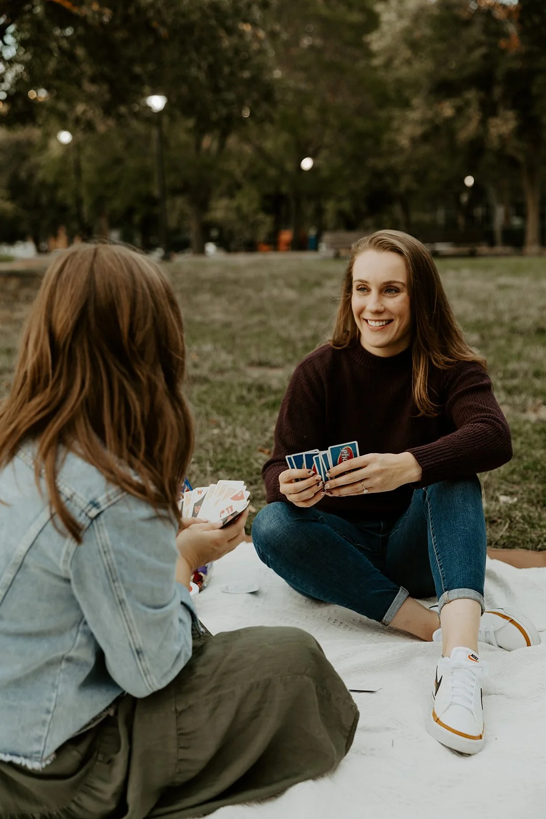 A couple playing cards in a park at a picnic