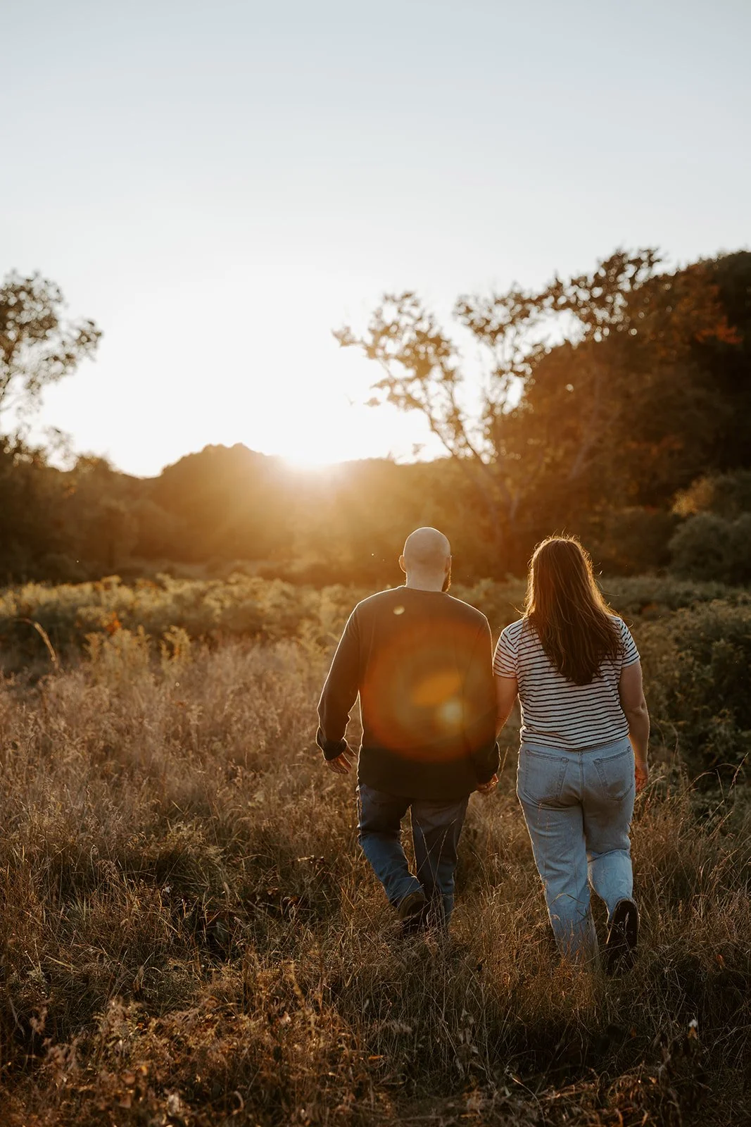 A couple in a field taking sunset engagement photos