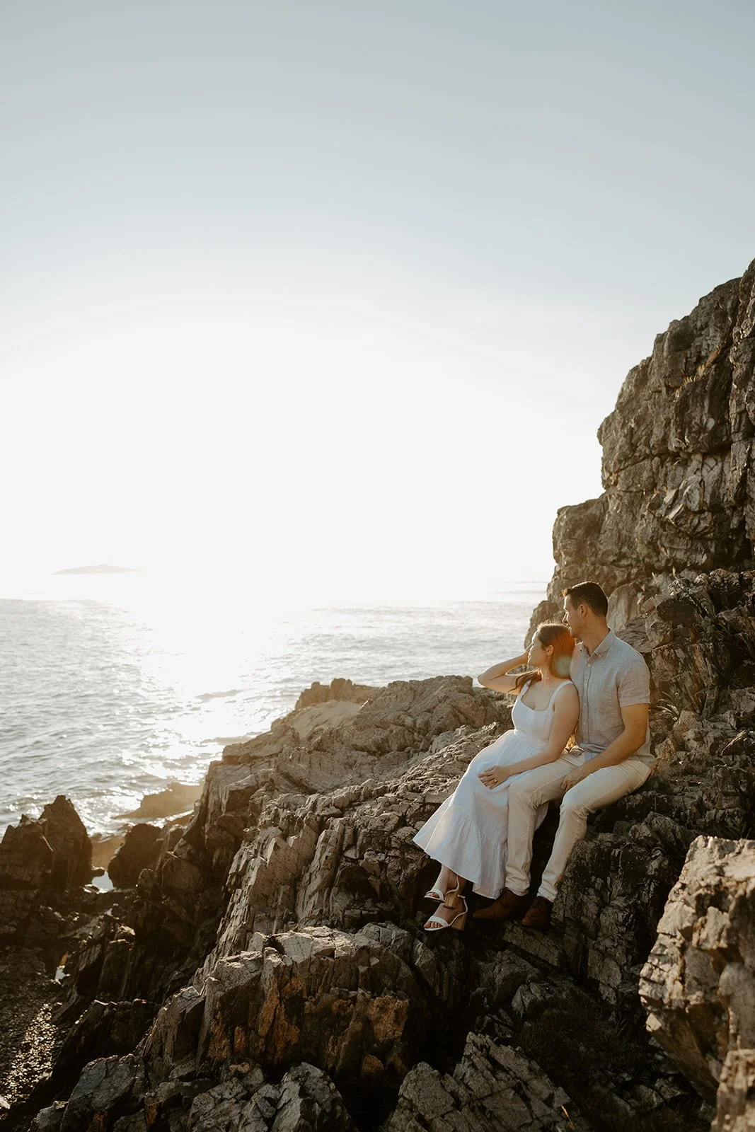 A couple sitting on rocks at one of the best Massachusetts engagement photo locations