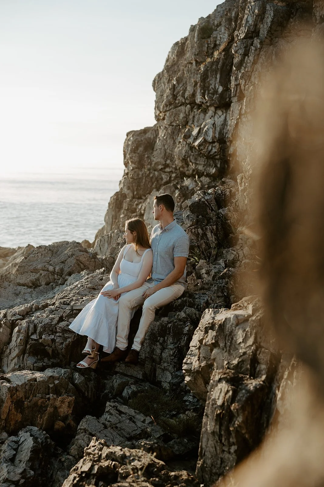 A couple sitting on rocks at one of the best Massachusetts engagement photo locations