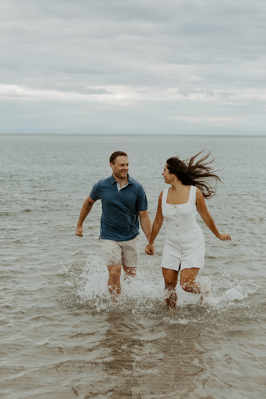 A couple running through the Ocean for engagement photos