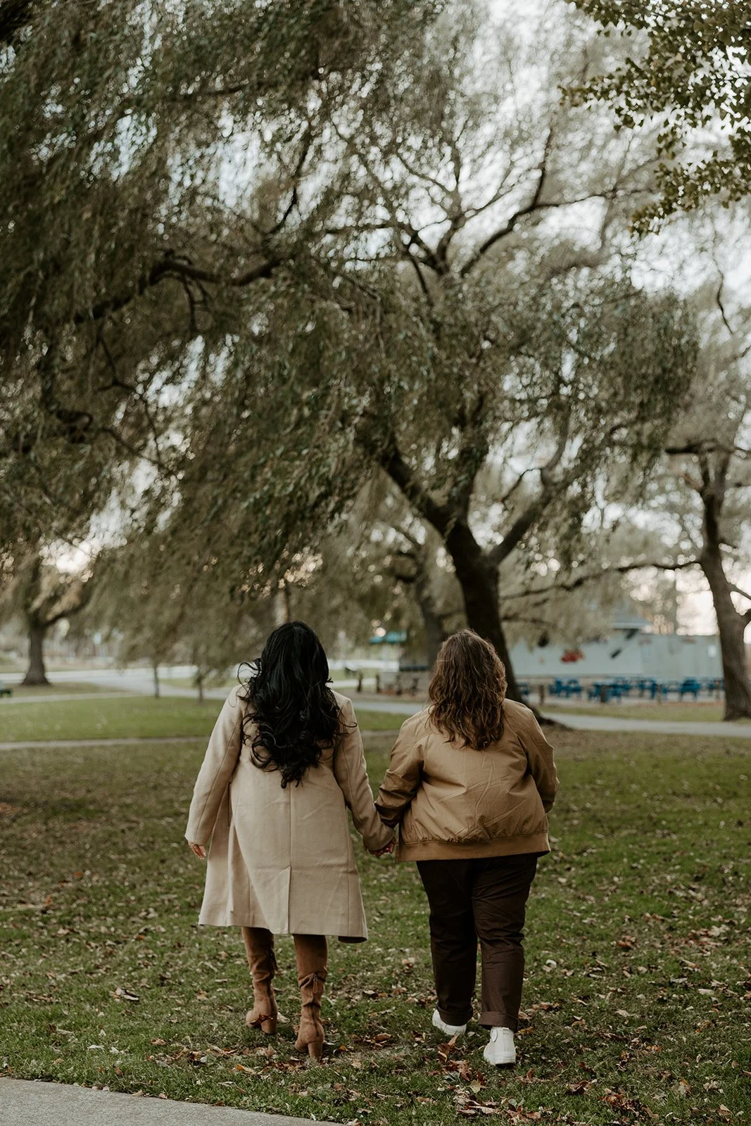 A couple taking engagement photos in front of willow trees at Salem Willows