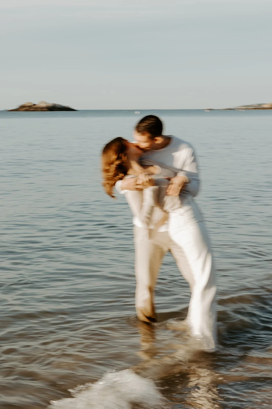 A couple taking beach engagement photos at Singing Beach 