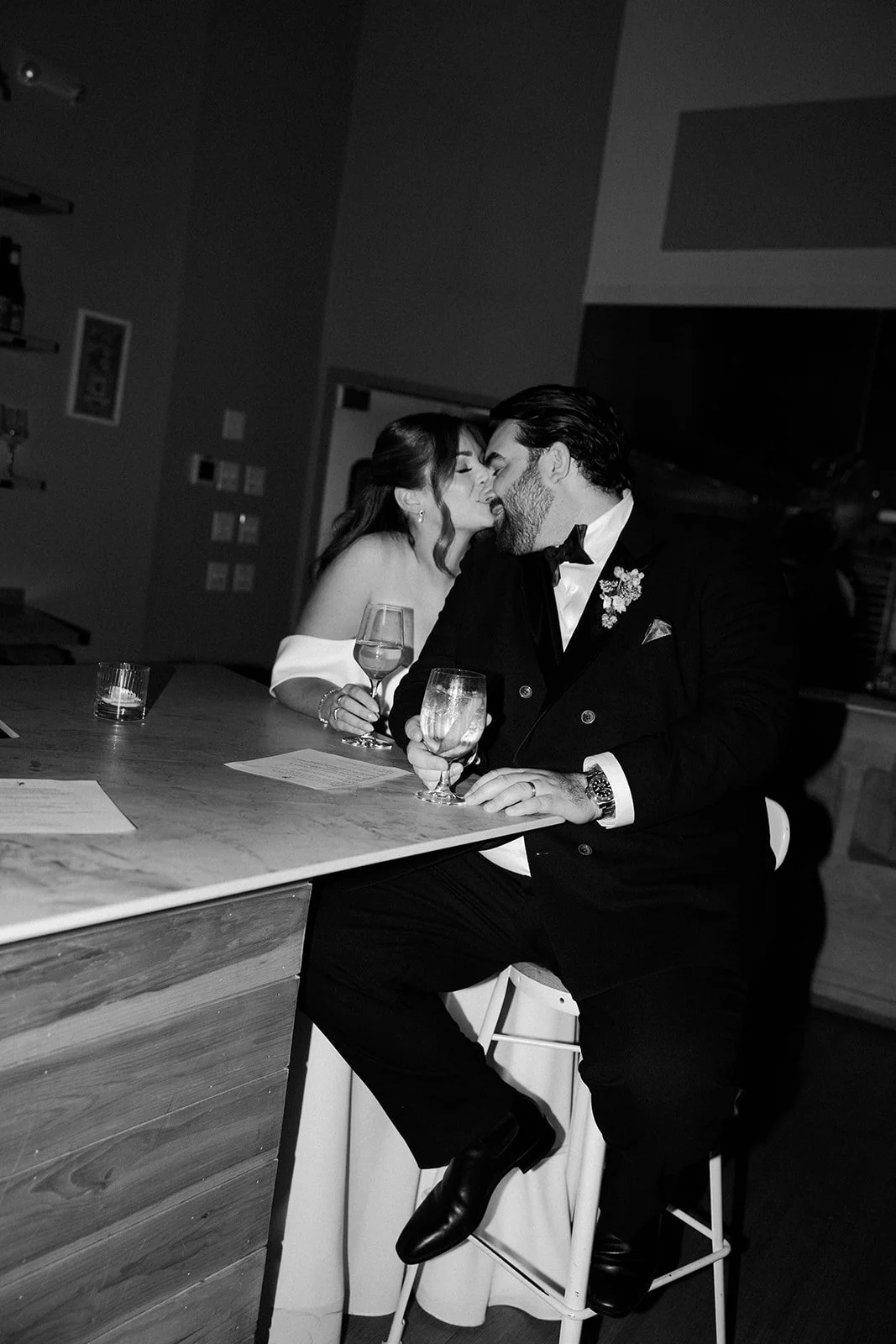 A couple kissing at a bar at their restaurant wedding