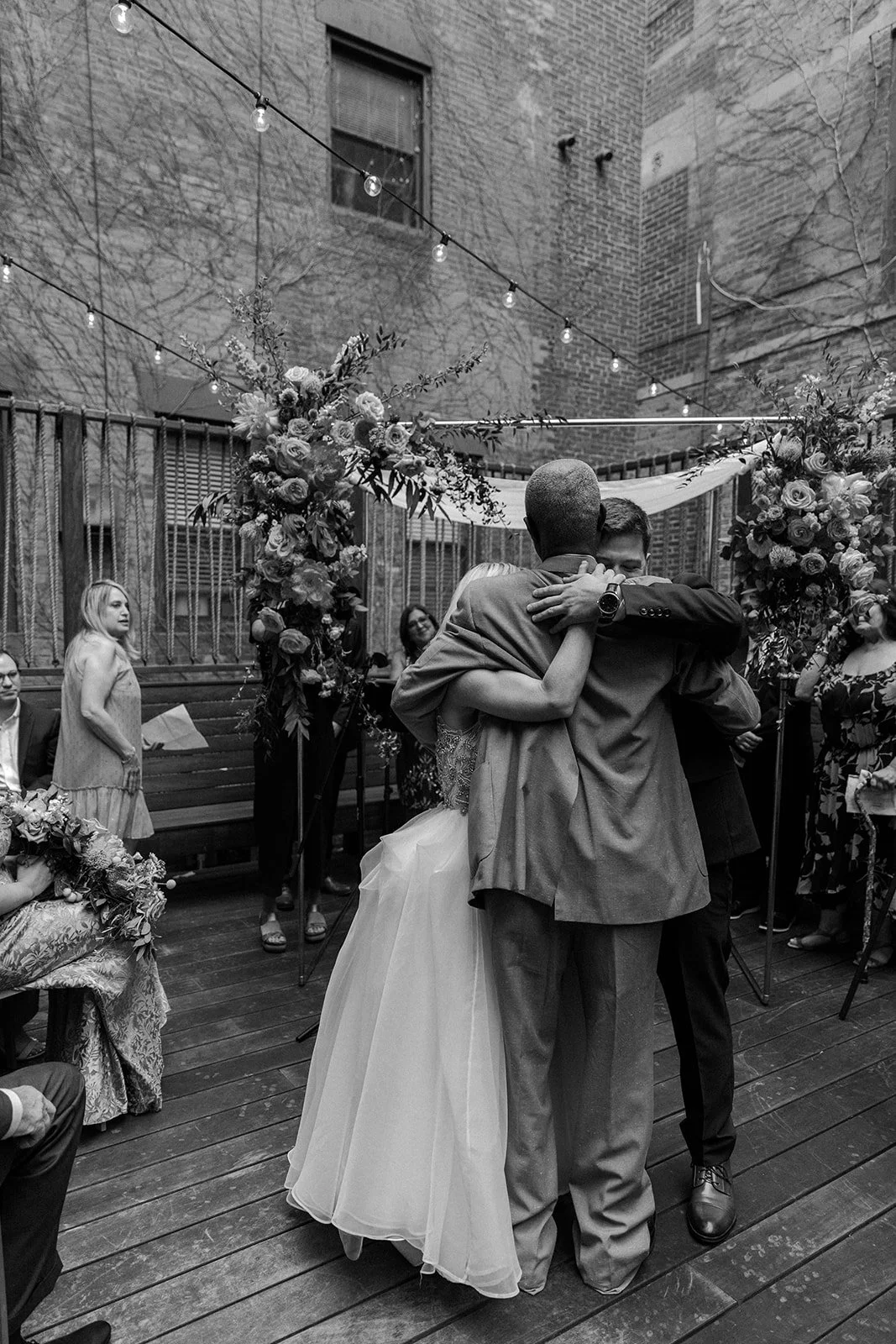 A bride hugging her dad and husband at the end of the aisle