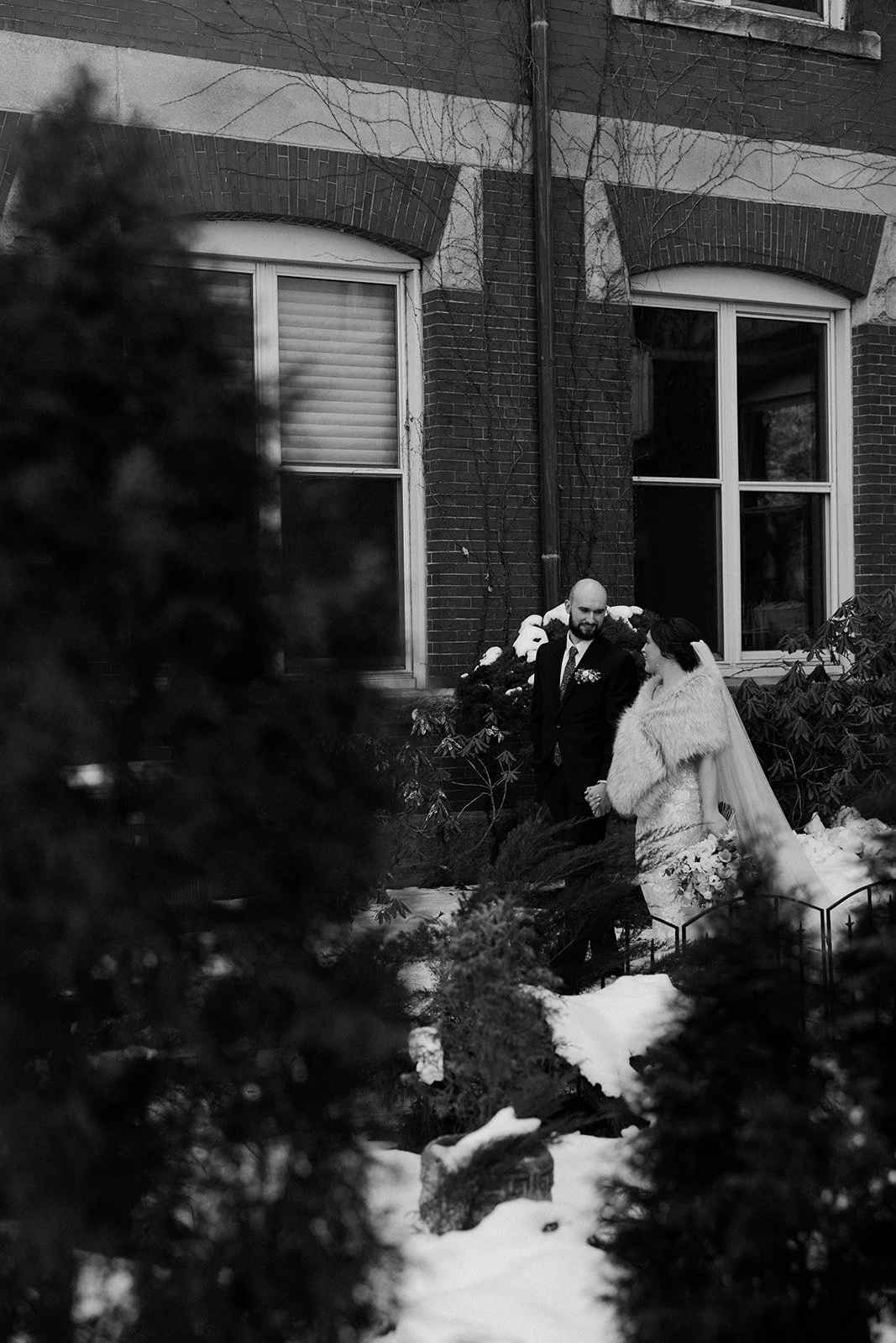A black and white photo of a bride and groom in the snow