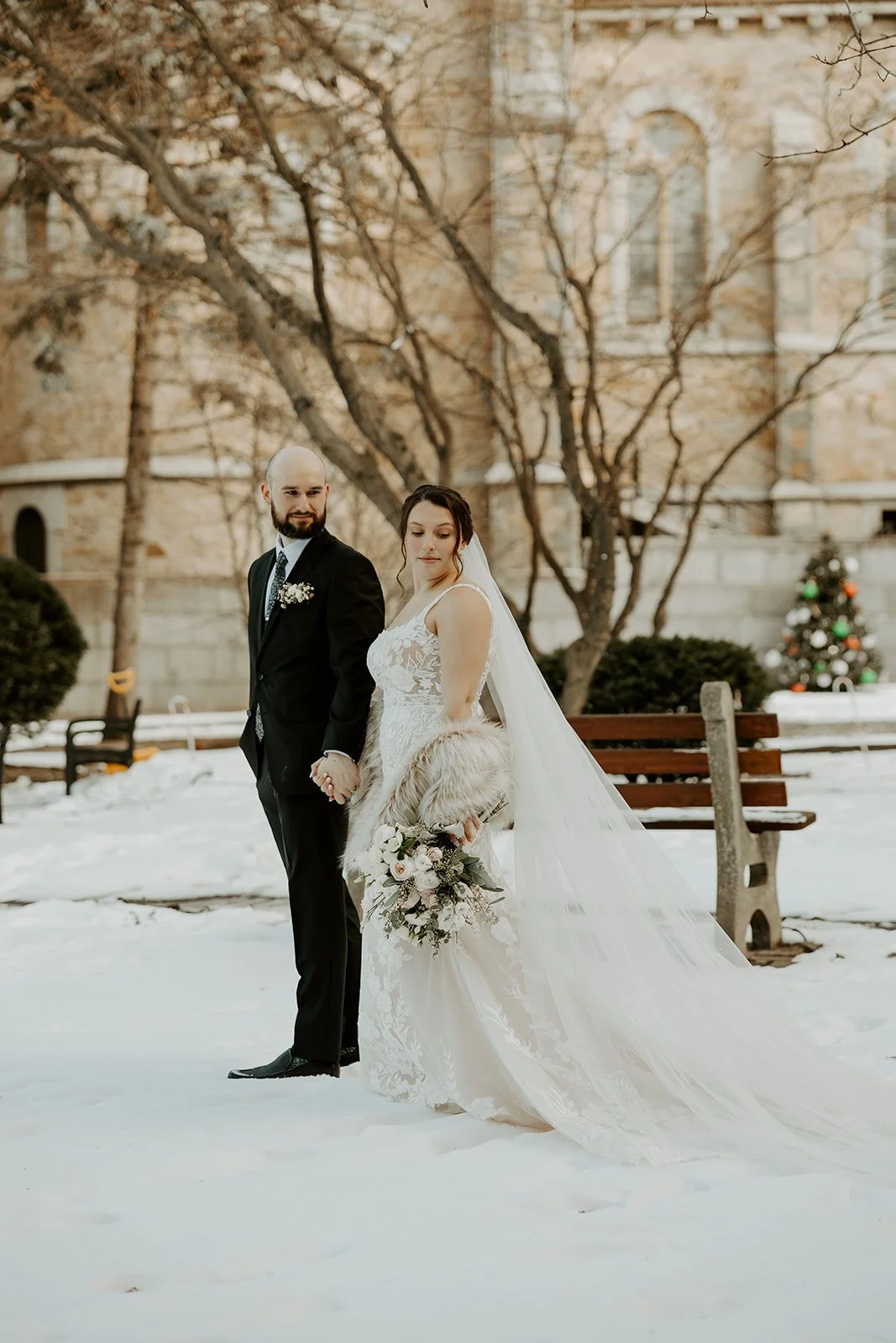 A bride and groom walking through the snow at their Boston wedding venue