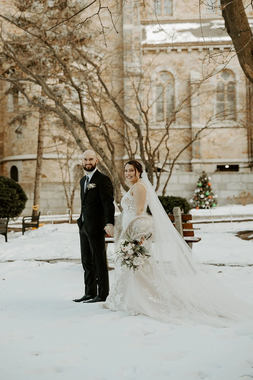 A bride and groom walking through the snow at their Boston wedding venue