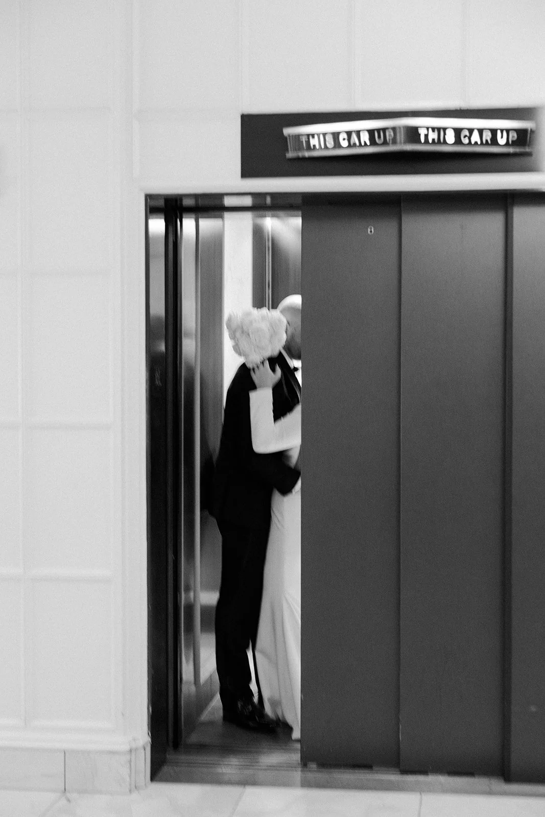 A bride and groom kissing in an elevator