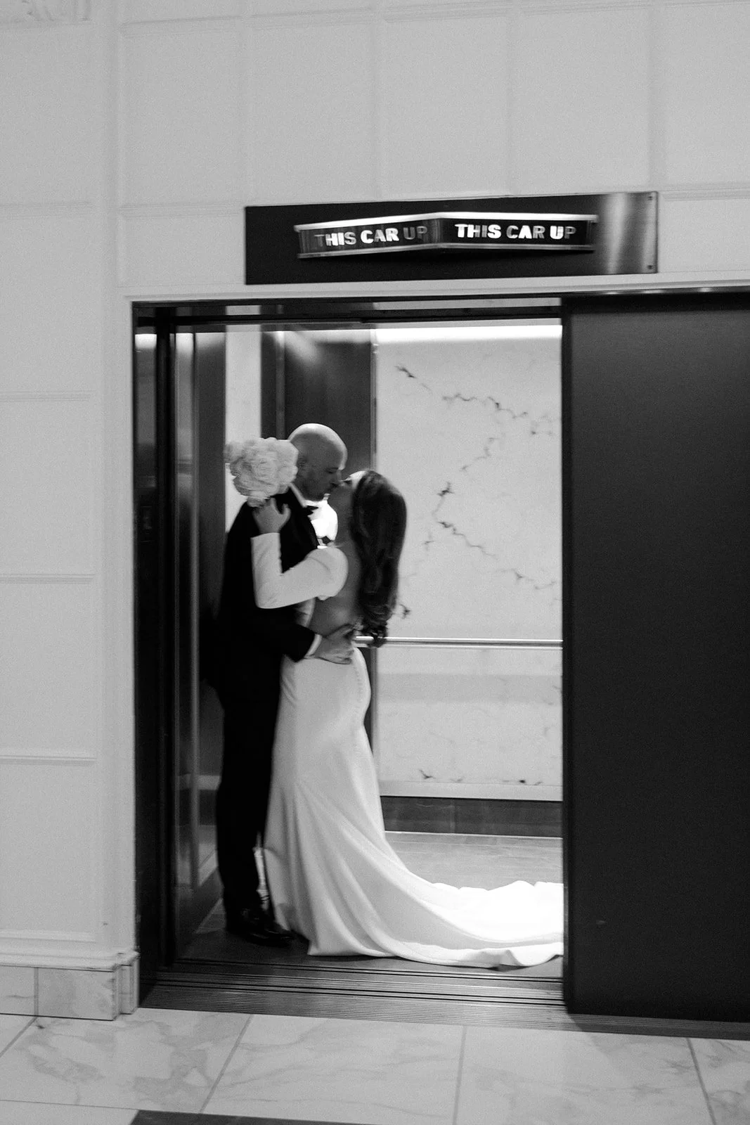 A bride and groom kissing in an elevator