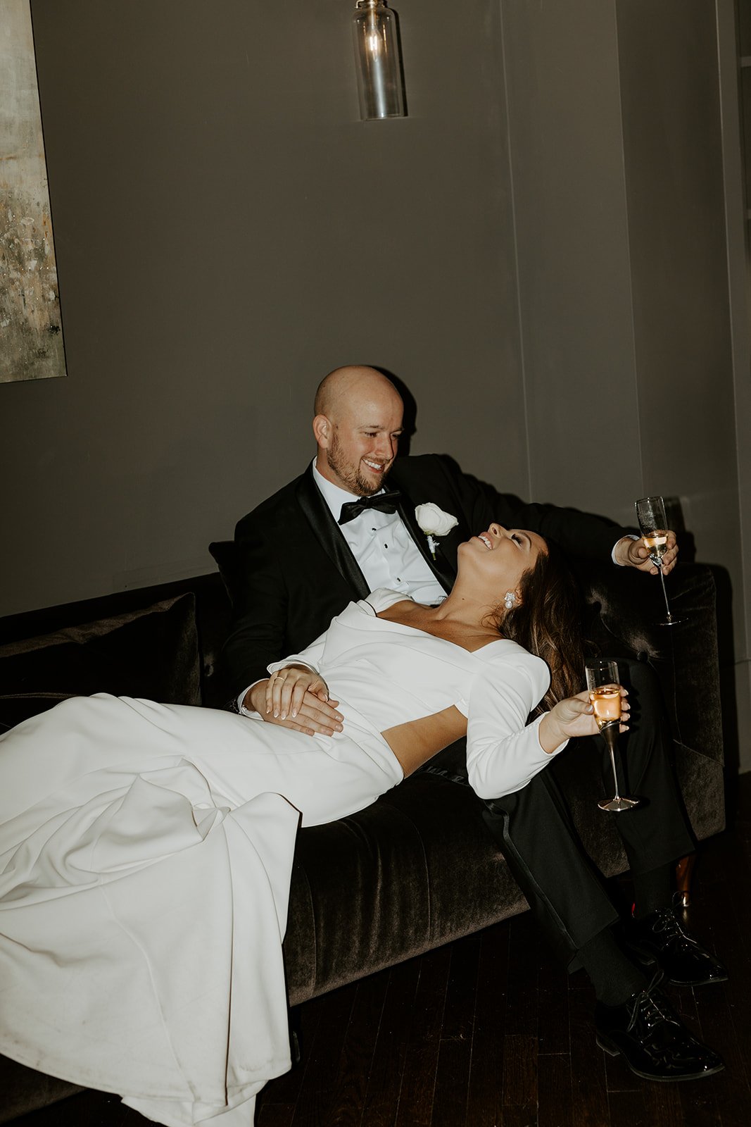 A couple on a couch posing for wedding portraits