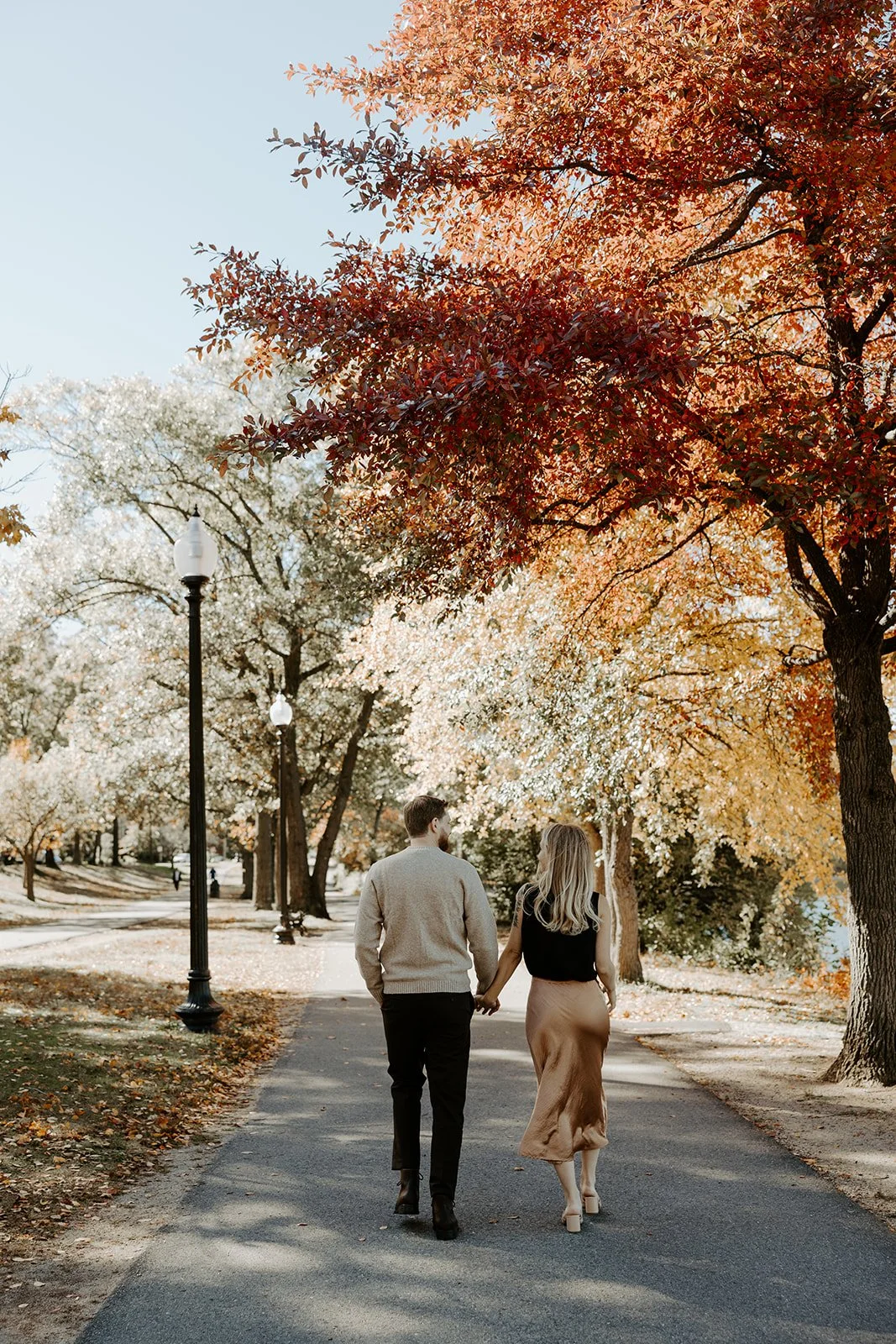 A couple wearing fall engagement photo outfits in a park