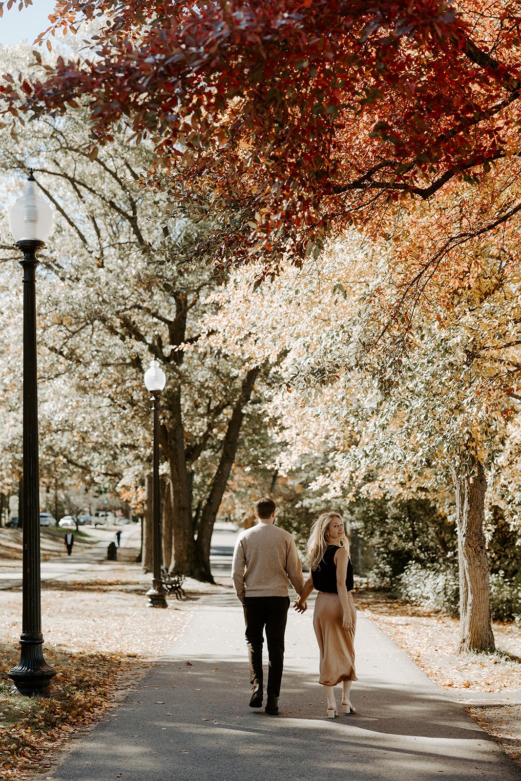 A couple wearing fall engagement photo outfits in a park