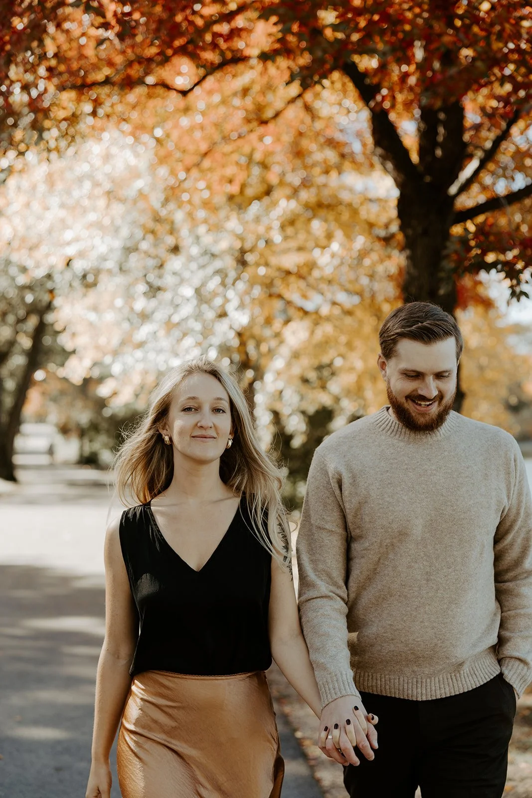A couple wearing fall engagement photo outfits in a park