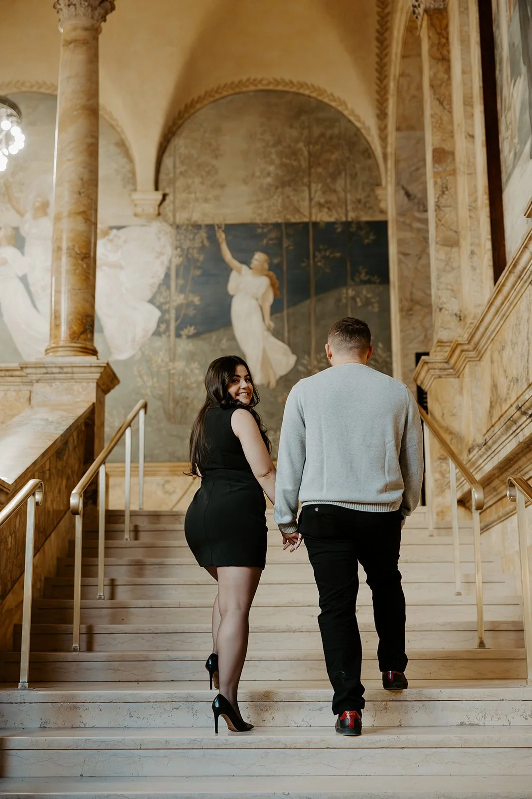 A couple taking engagement photos inside the Boston Public Library