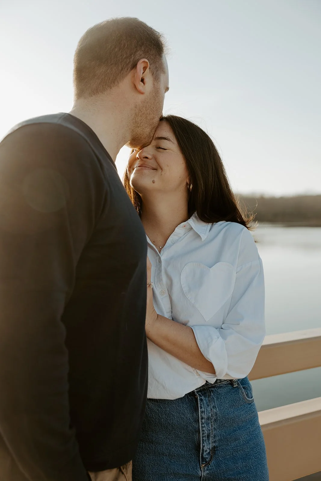 A couple posing for engagement photos in front of a pond