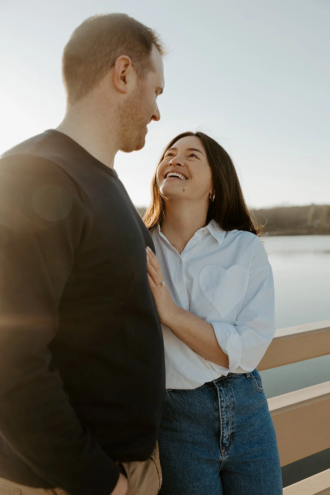 A couple posing for engagement photos in front of a pond