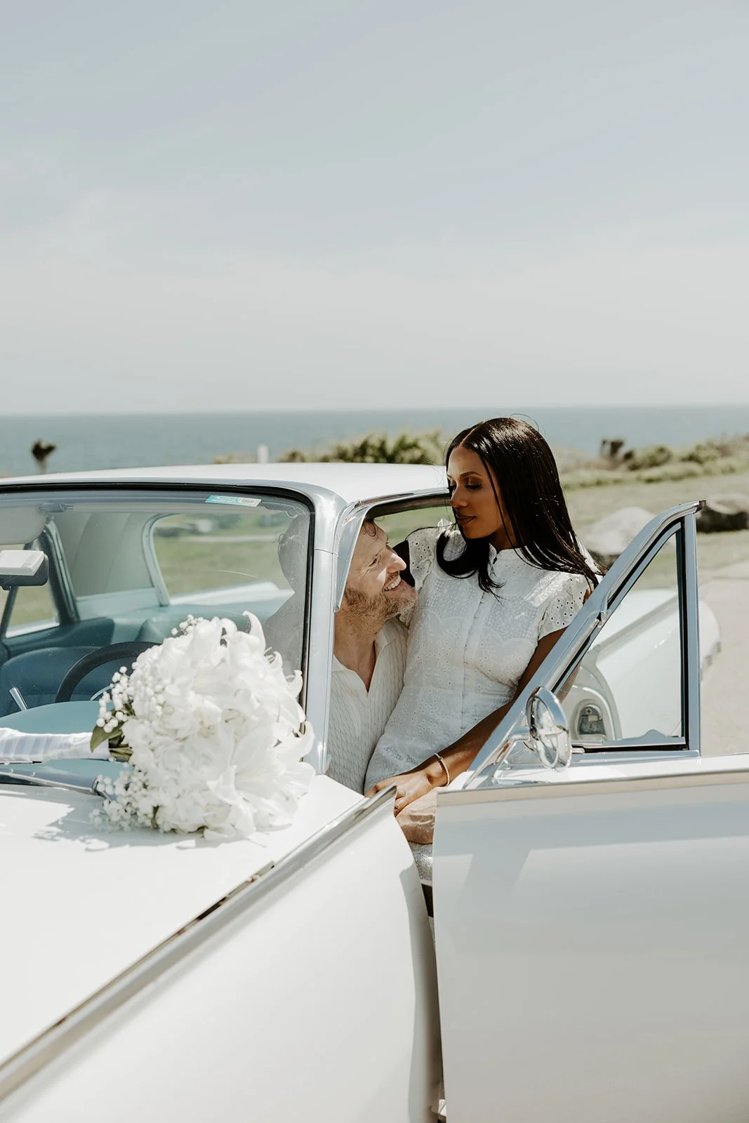 A couple taking engagement photos in a vintage car