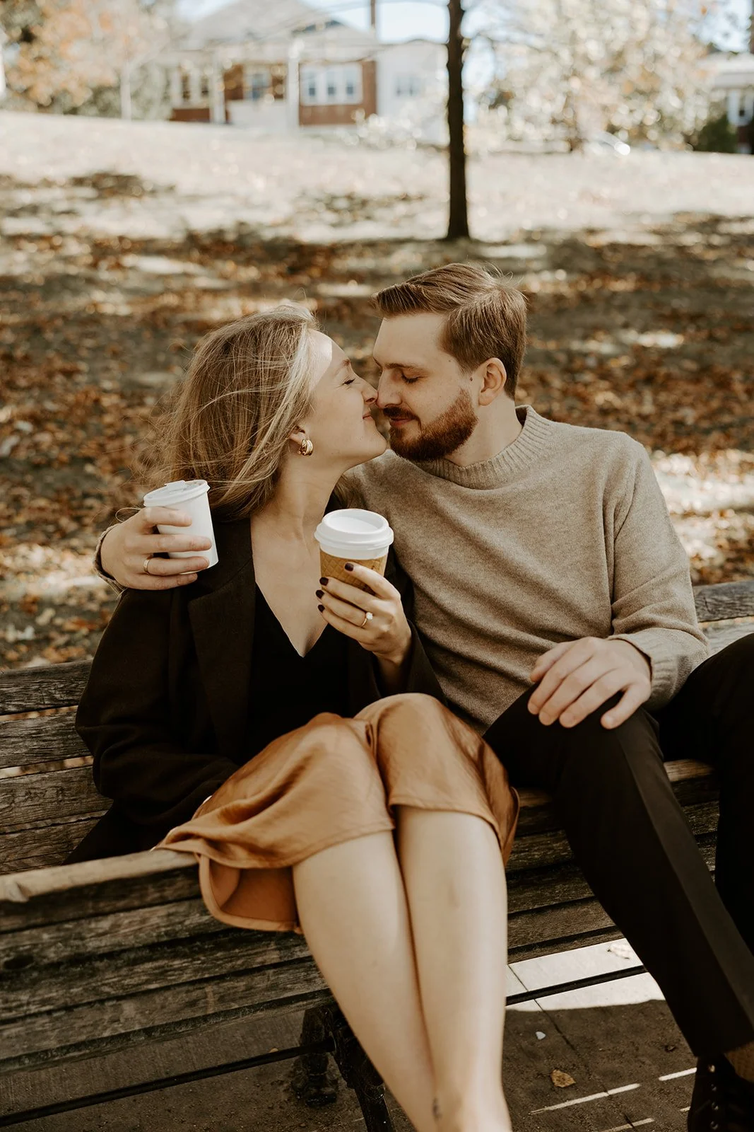 A couple kissing on a bench during fall engagement photos