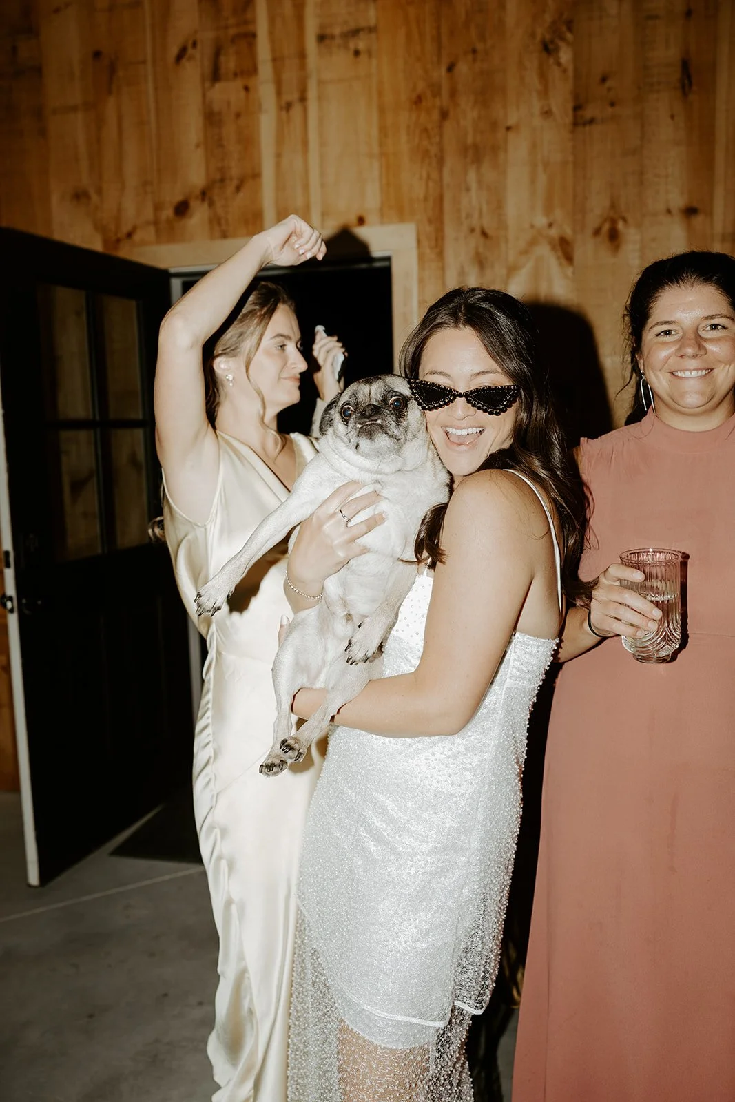 A bride holding her dog at her wedding reception