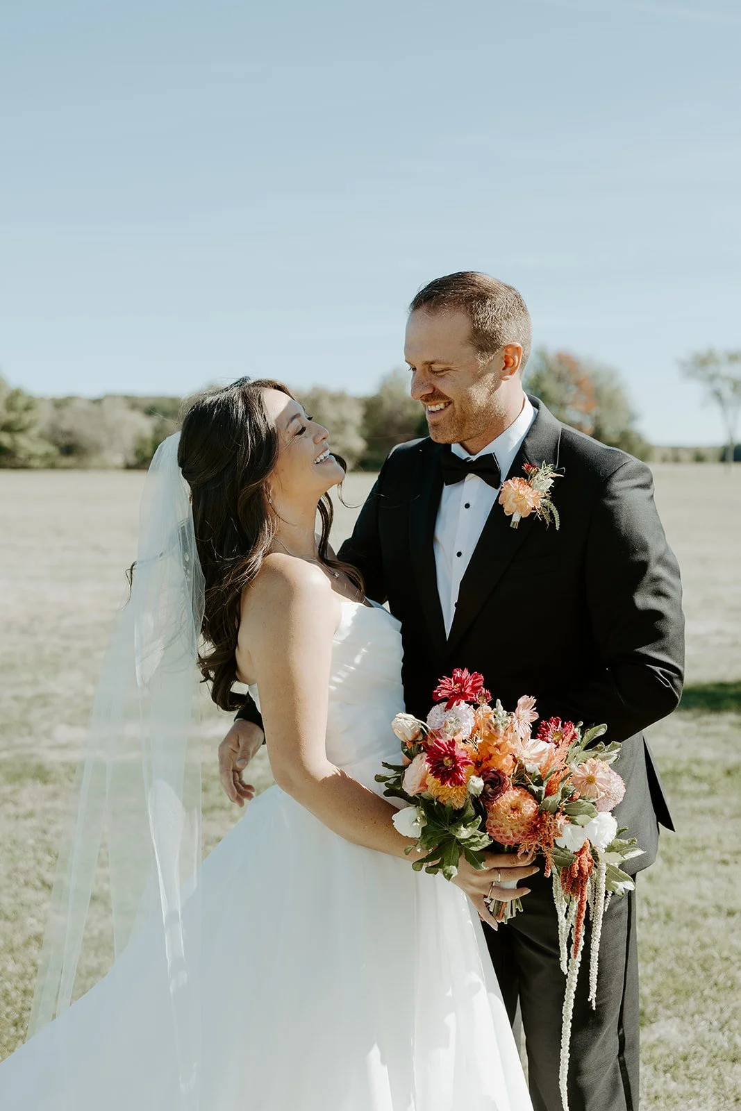 A groom kissing a bride on the cheek at a backyard wedding