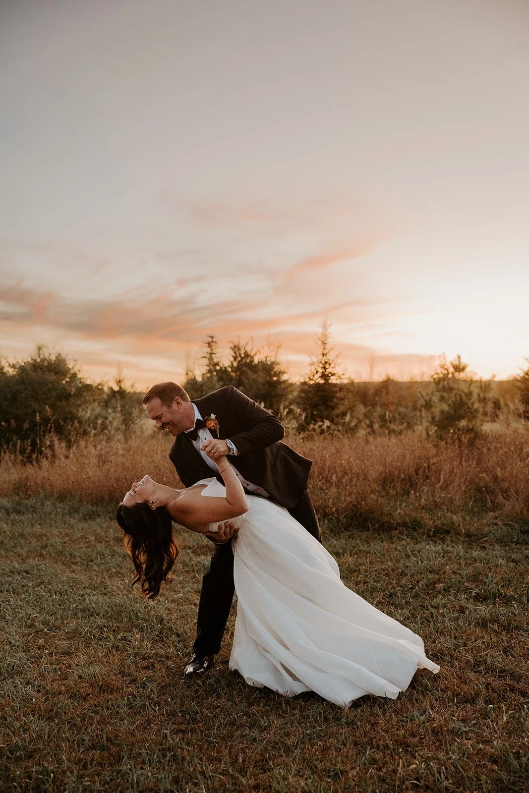A bride and groom taking sunset photos at their backyard wedding