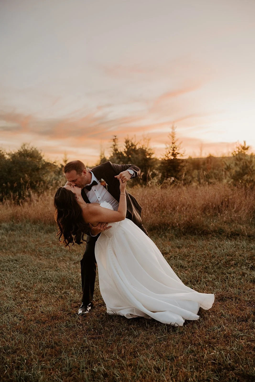 A bride and groom taking sunset photos at their backyard wedding