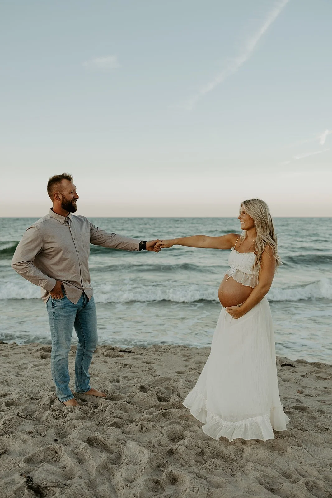 A couple dancing on the beach for a maternity photoshoot