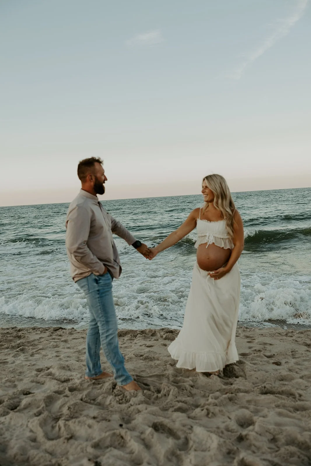A couple dancing on the beach for a maternity photoshoot