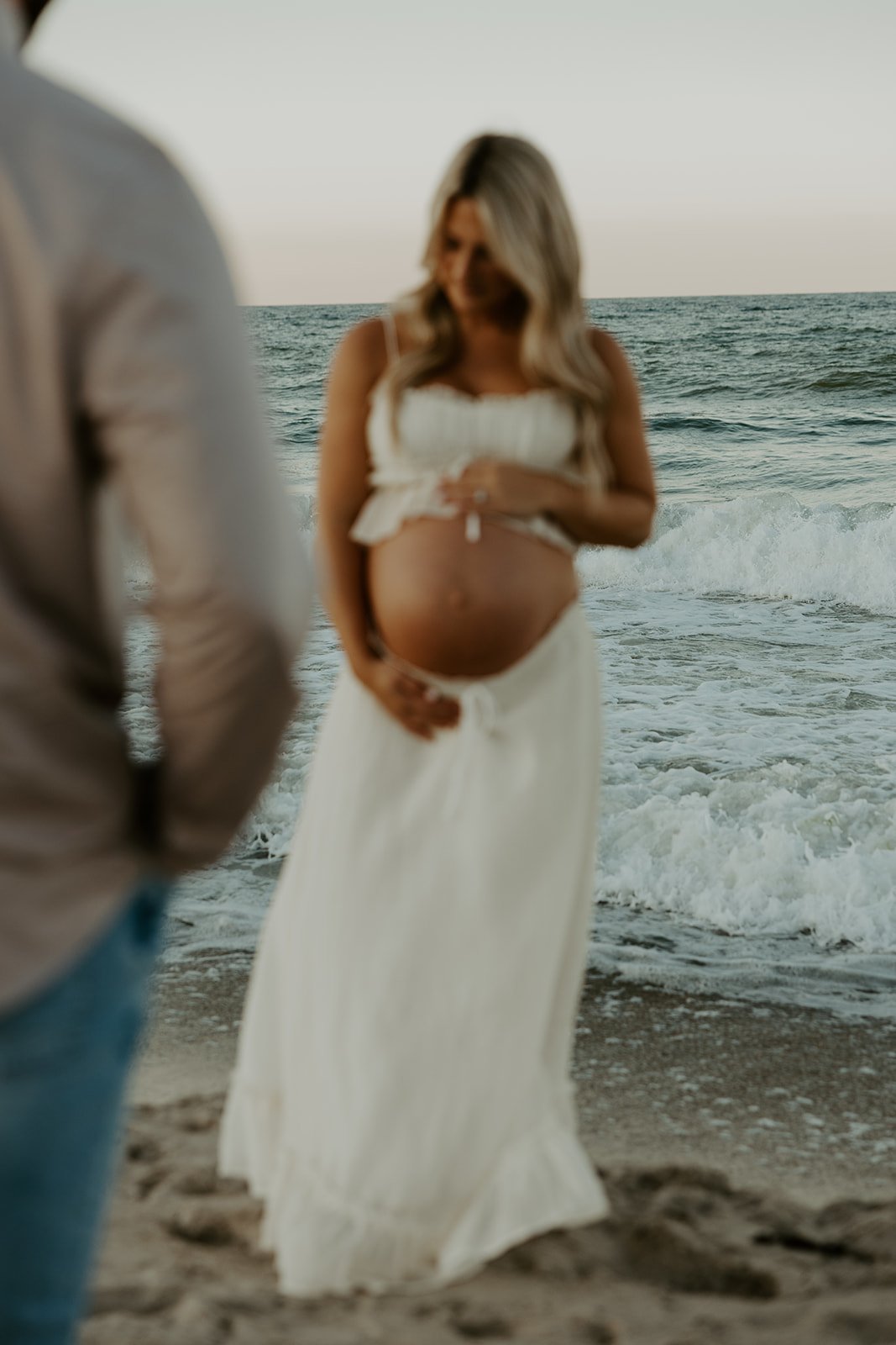 A man looking at his pregnant wife in beach maternity photos