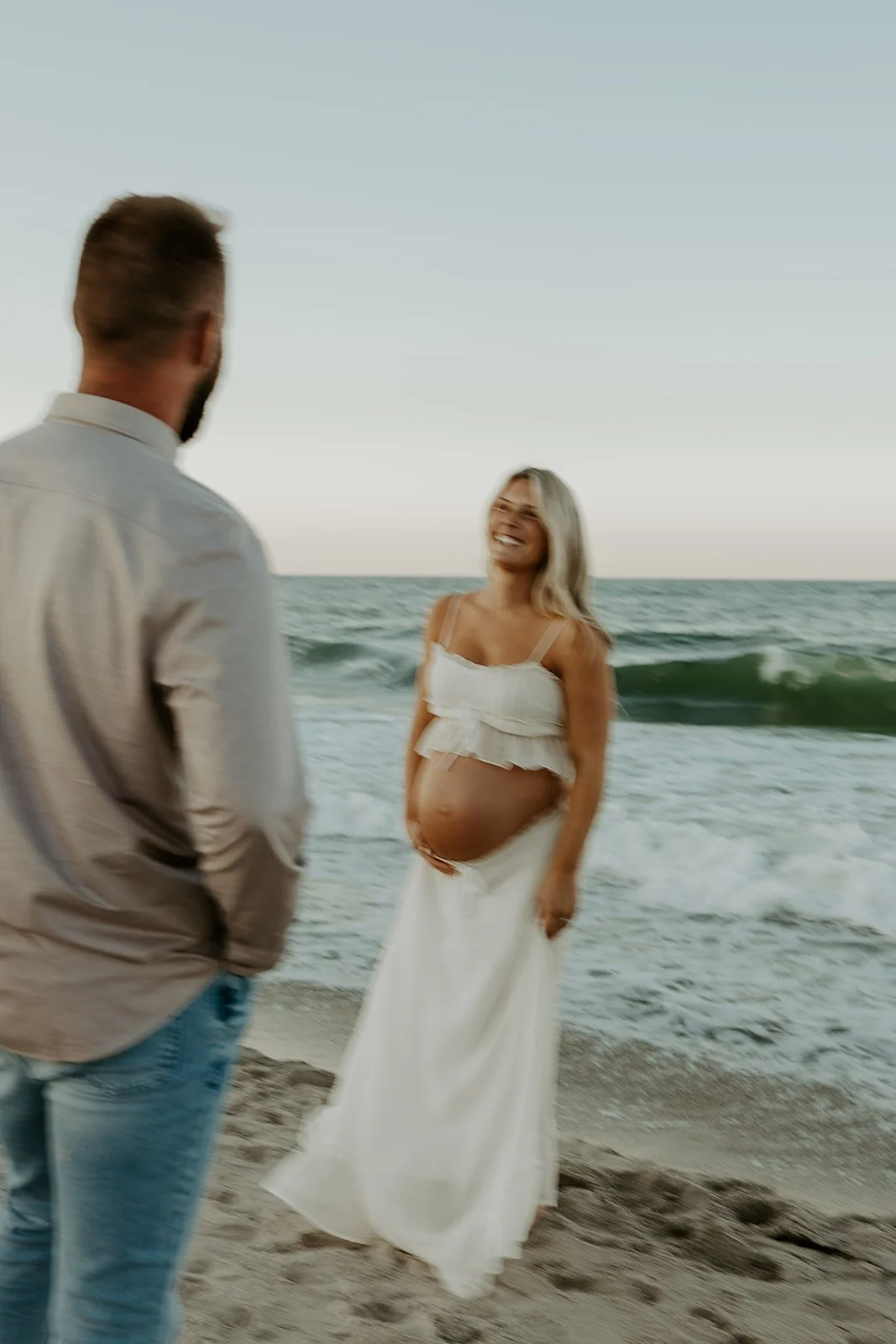 A man looking at his pregnant wife in beach maternity photos