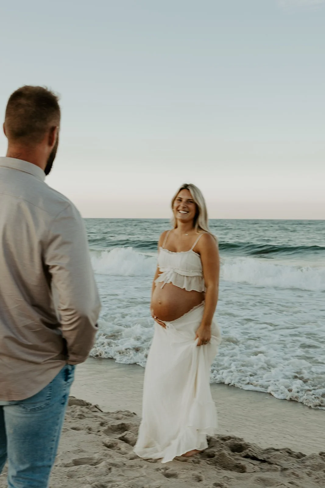 A man looking at his pregnant wife in beach maternity photos