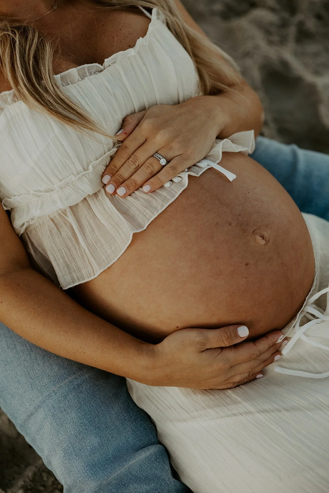 A woman showing off her beach maternity photo outfit