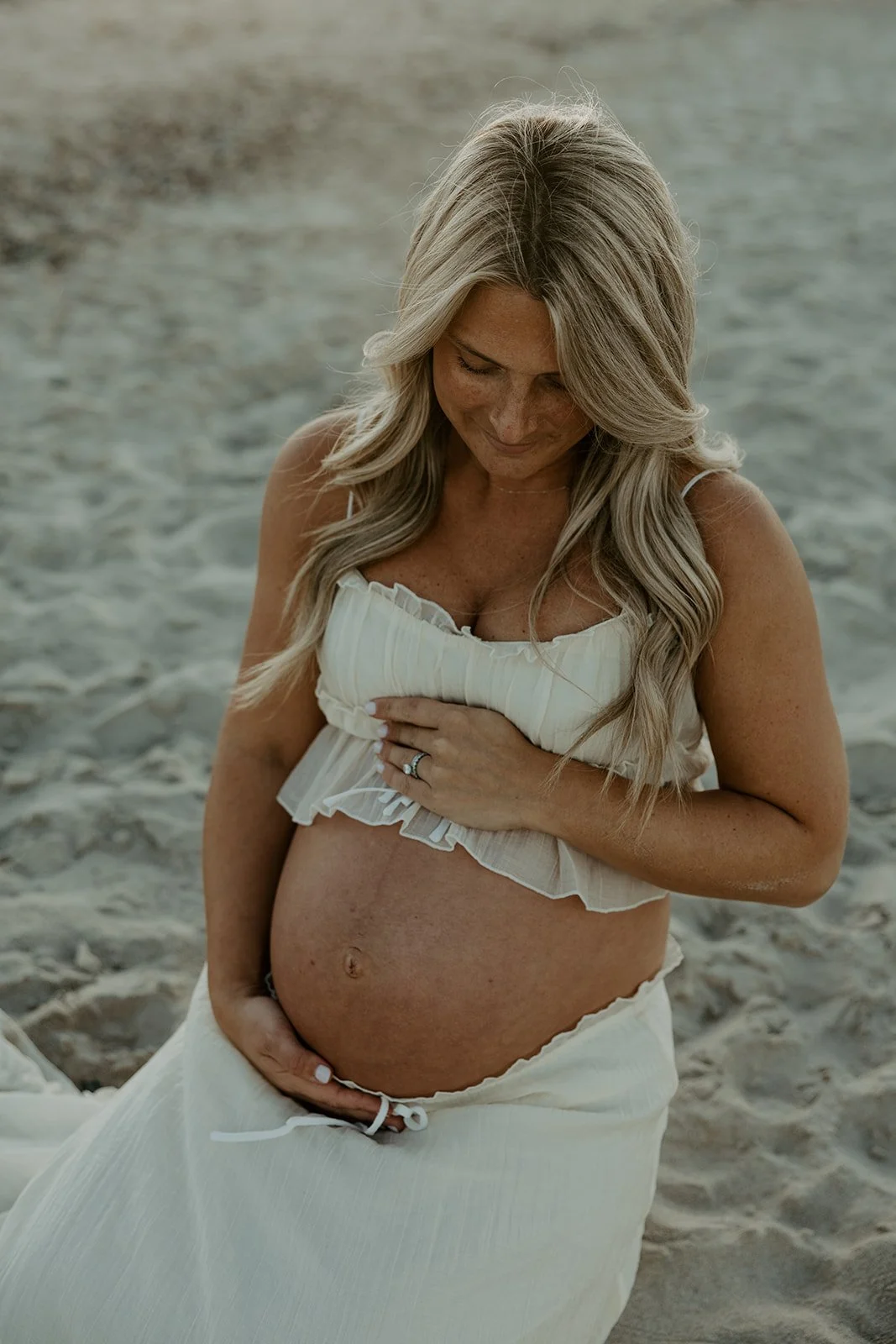 A woman posing for beach maternity photos