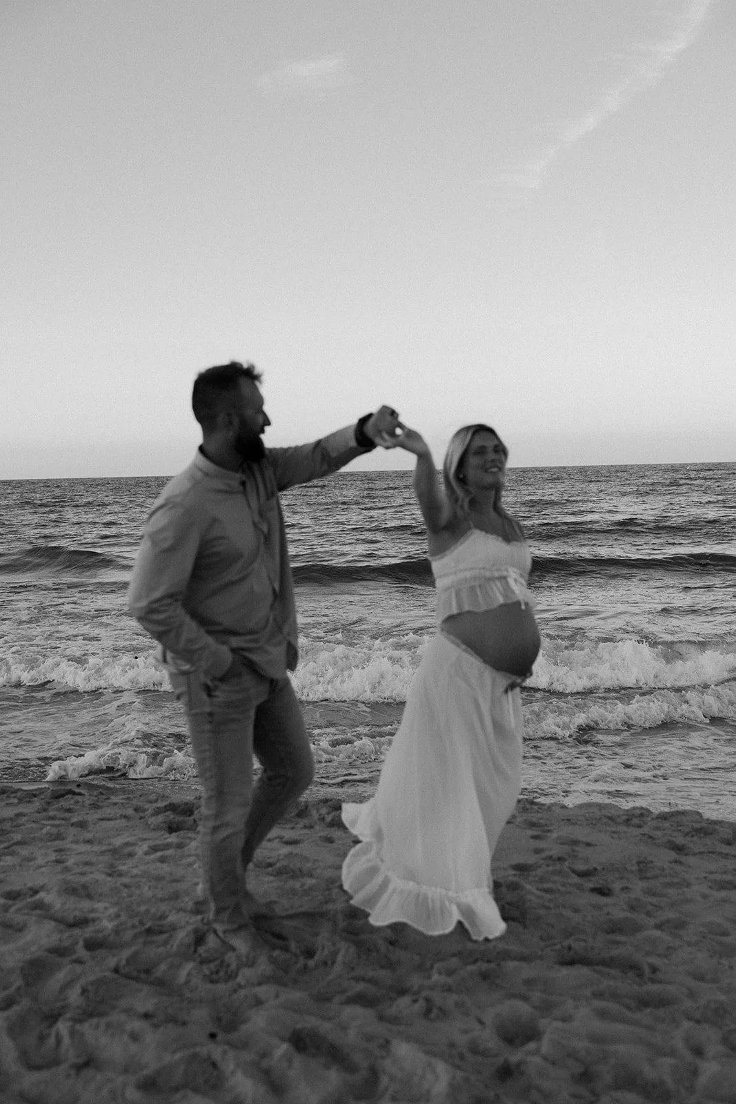 A couple dancing on the beach for maternity photos