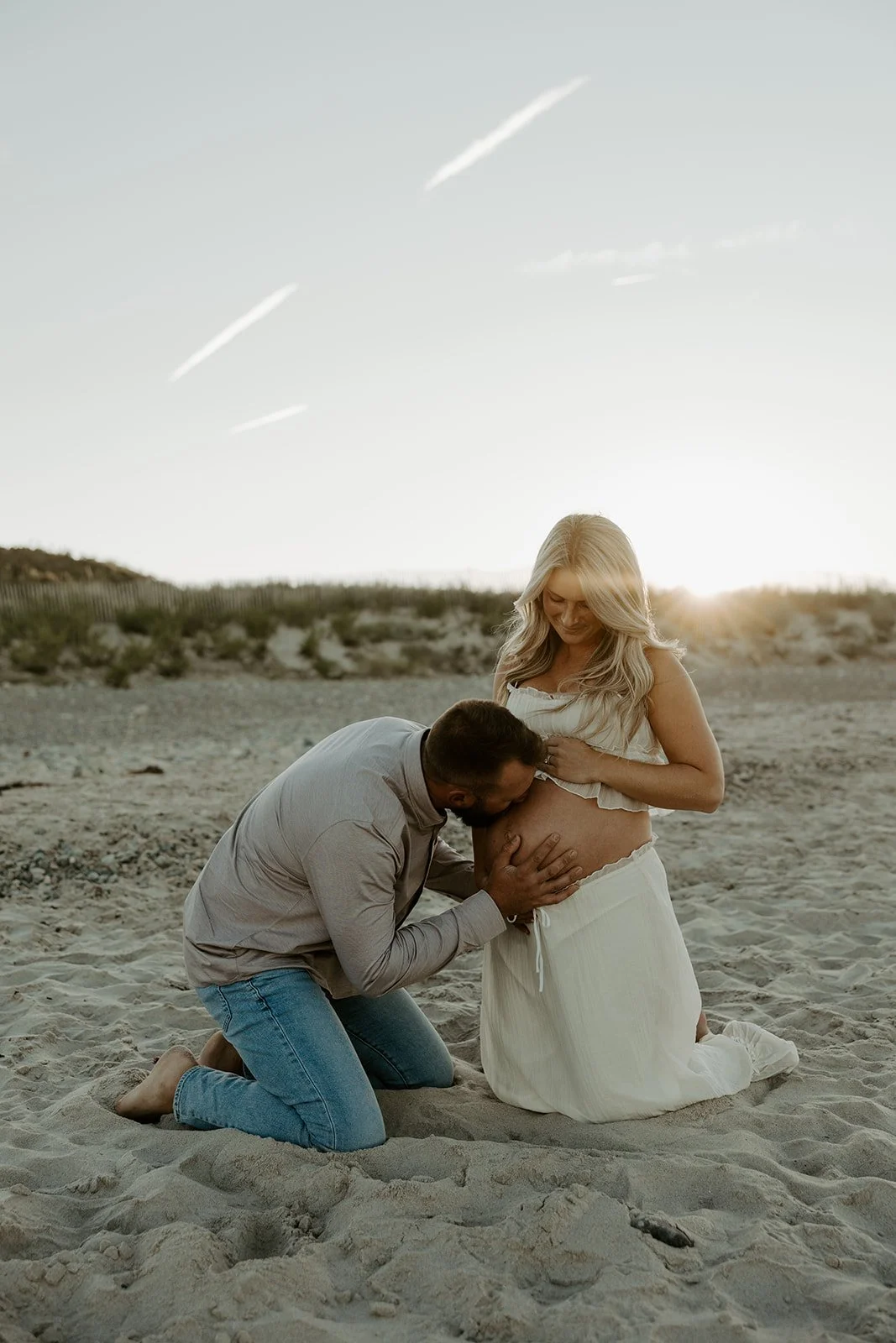 A couple posing for beach maternity photos