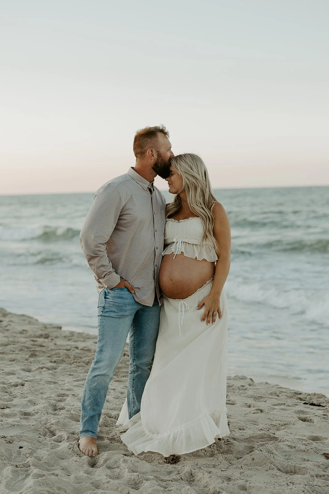 A couple posing for beach maternity photos