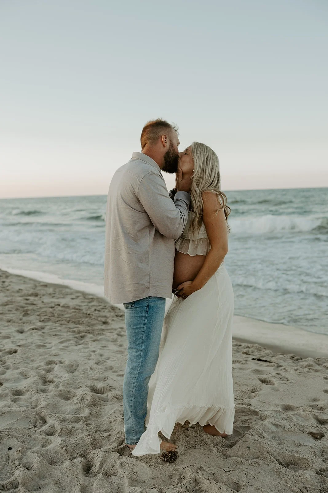 A couple posing for beach maternity photos