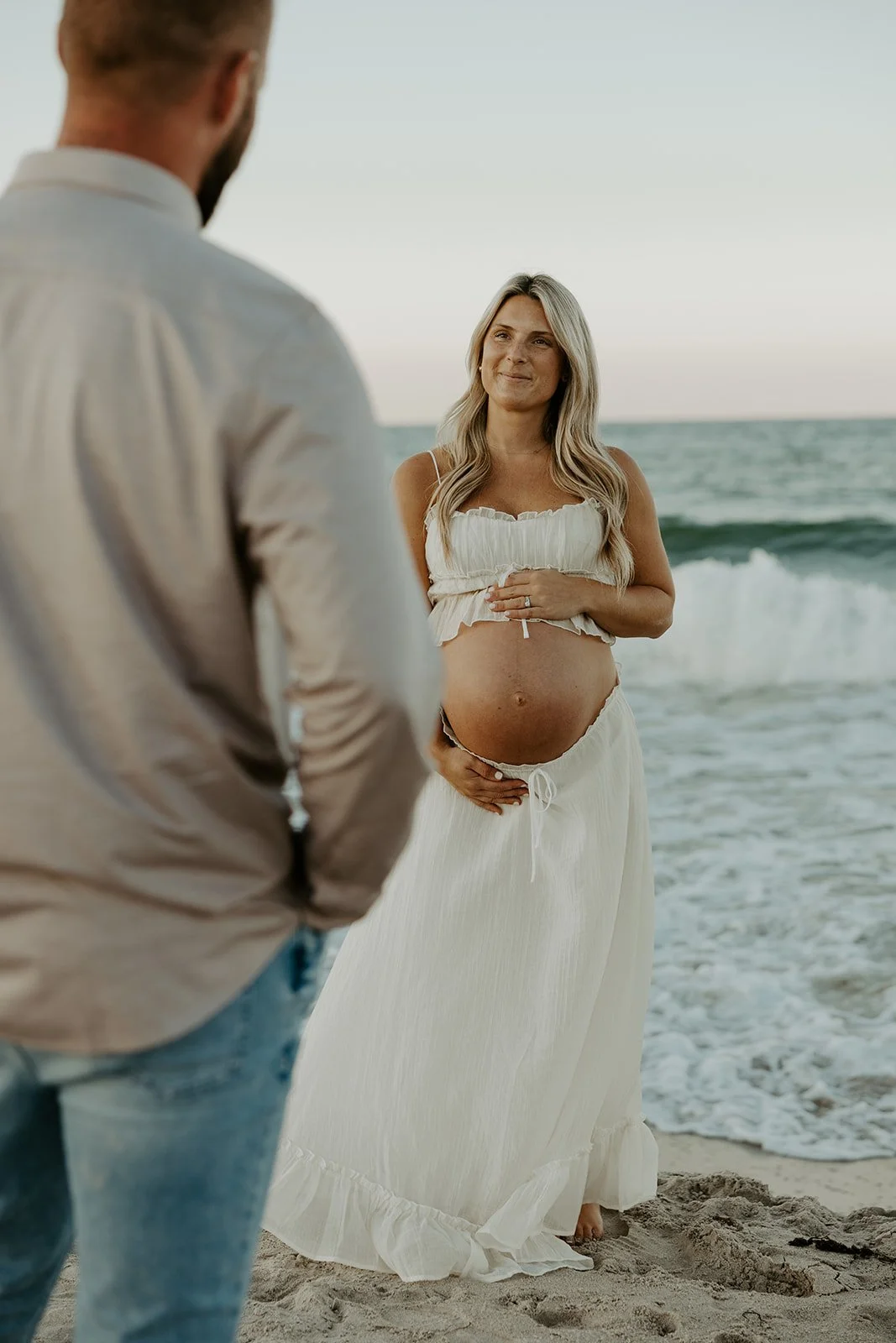 A couple posing for beach maternity photos