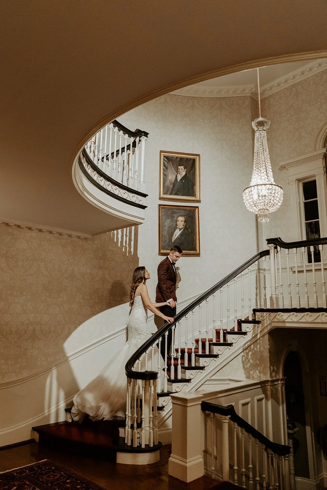 A bride and groom walking up a spiral staircase