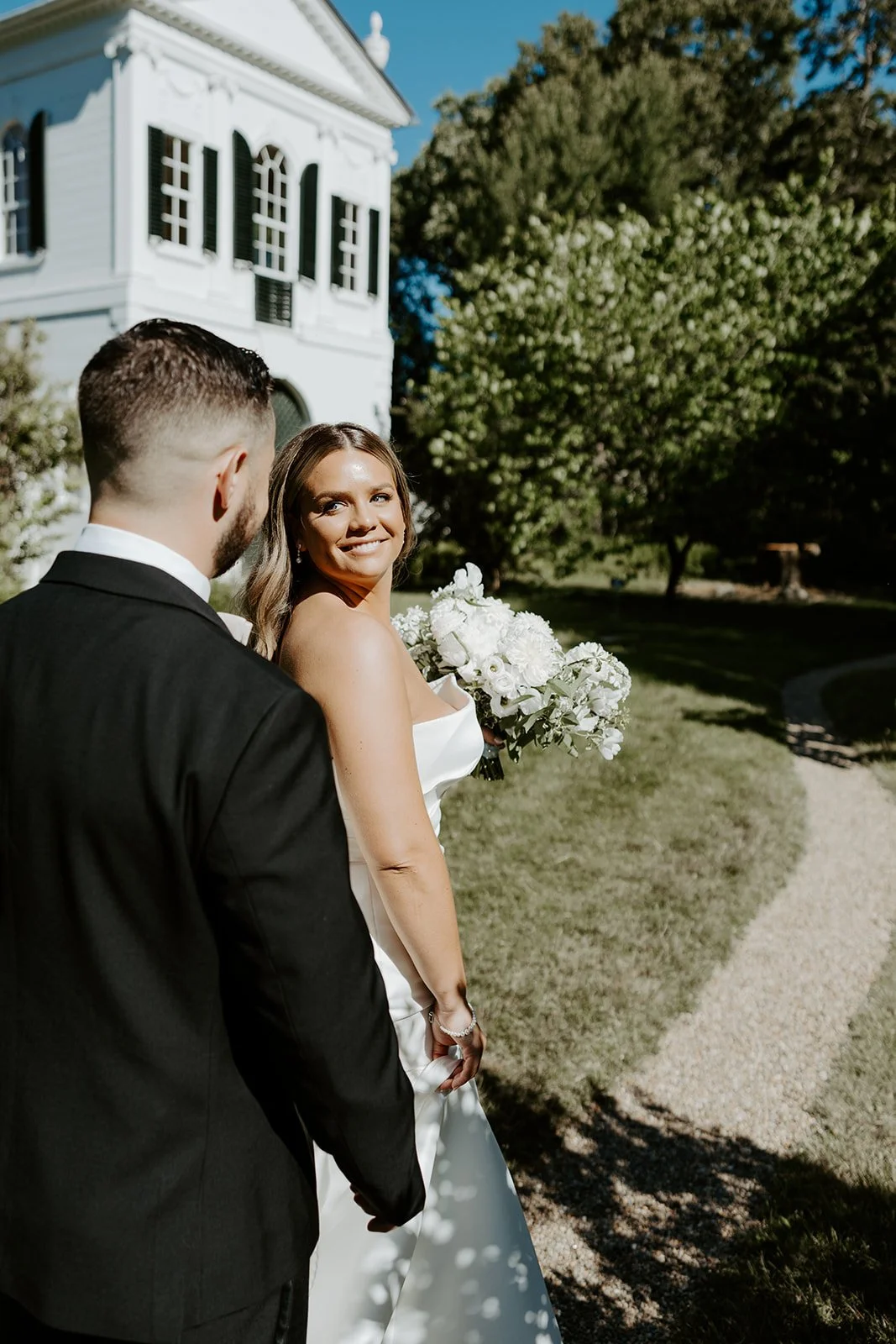 A bride and groom walking along the path at Glen Magna Farms