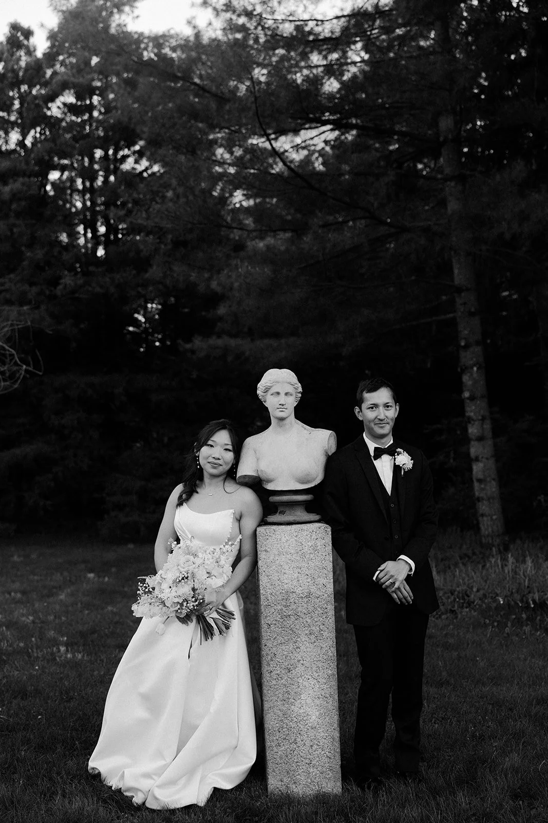 A bride and groom posing for wedding photos with a statue