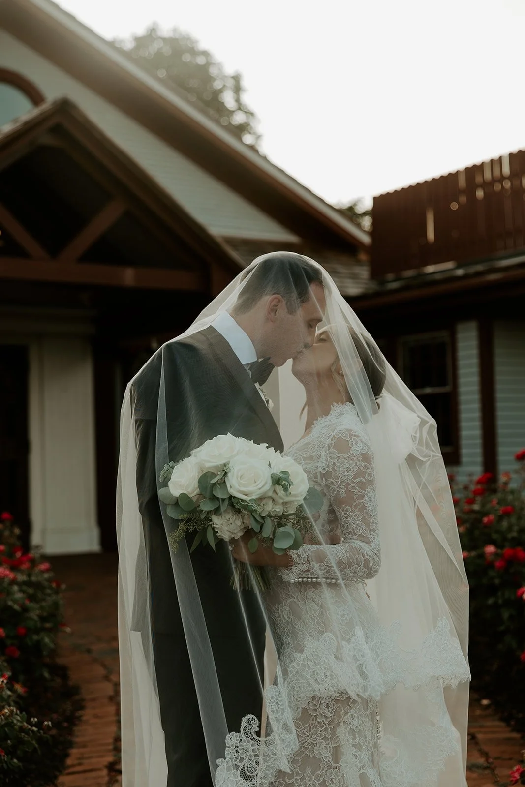 A bride and groom posing for wedding portraits under a veil in a blog post about how to plan a wedding