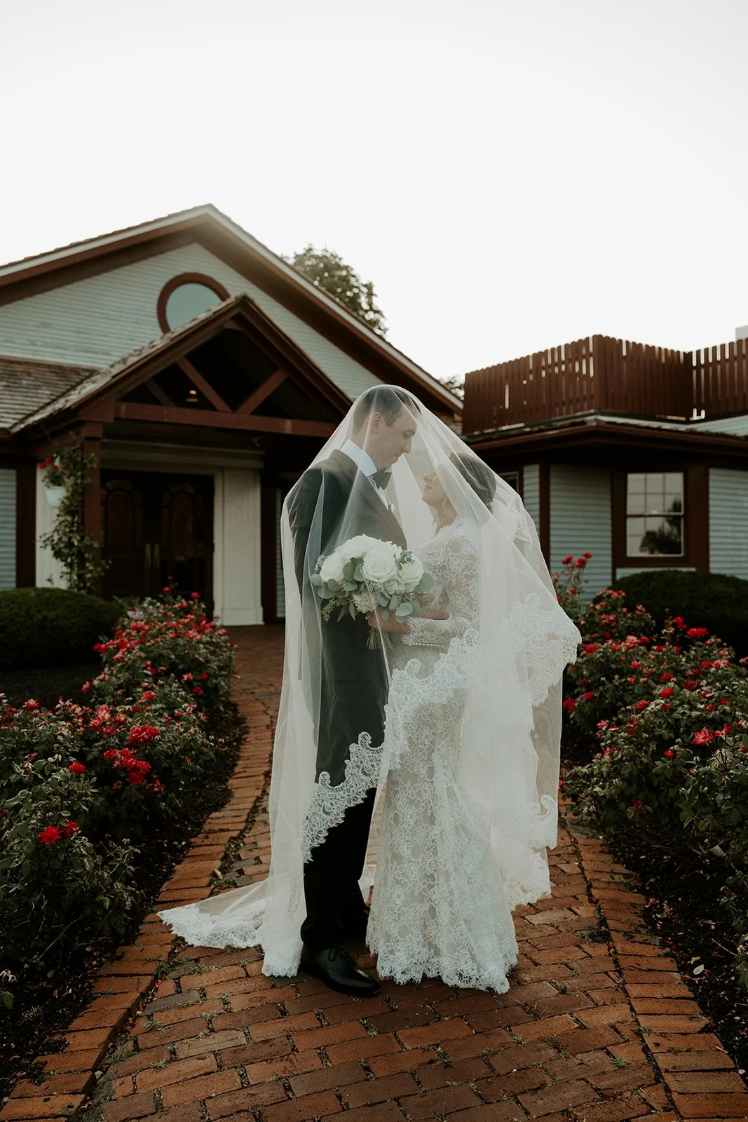 A bride and groom posing for wedding portraits under a veil in a blog post about how to plan a wedding