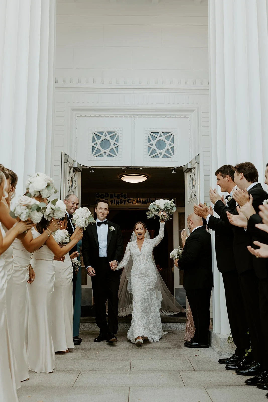 A bride and groom cheering after their wedding ceremony